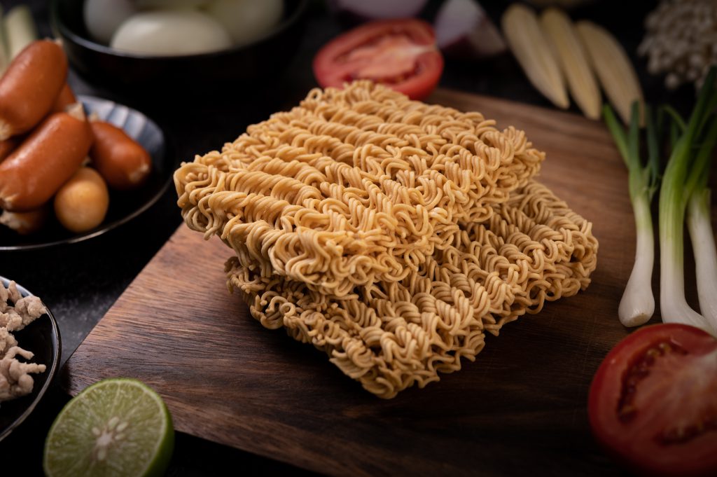 Noodles On A Wooden Cutting Board With Tomato, Lime, Spring Onio